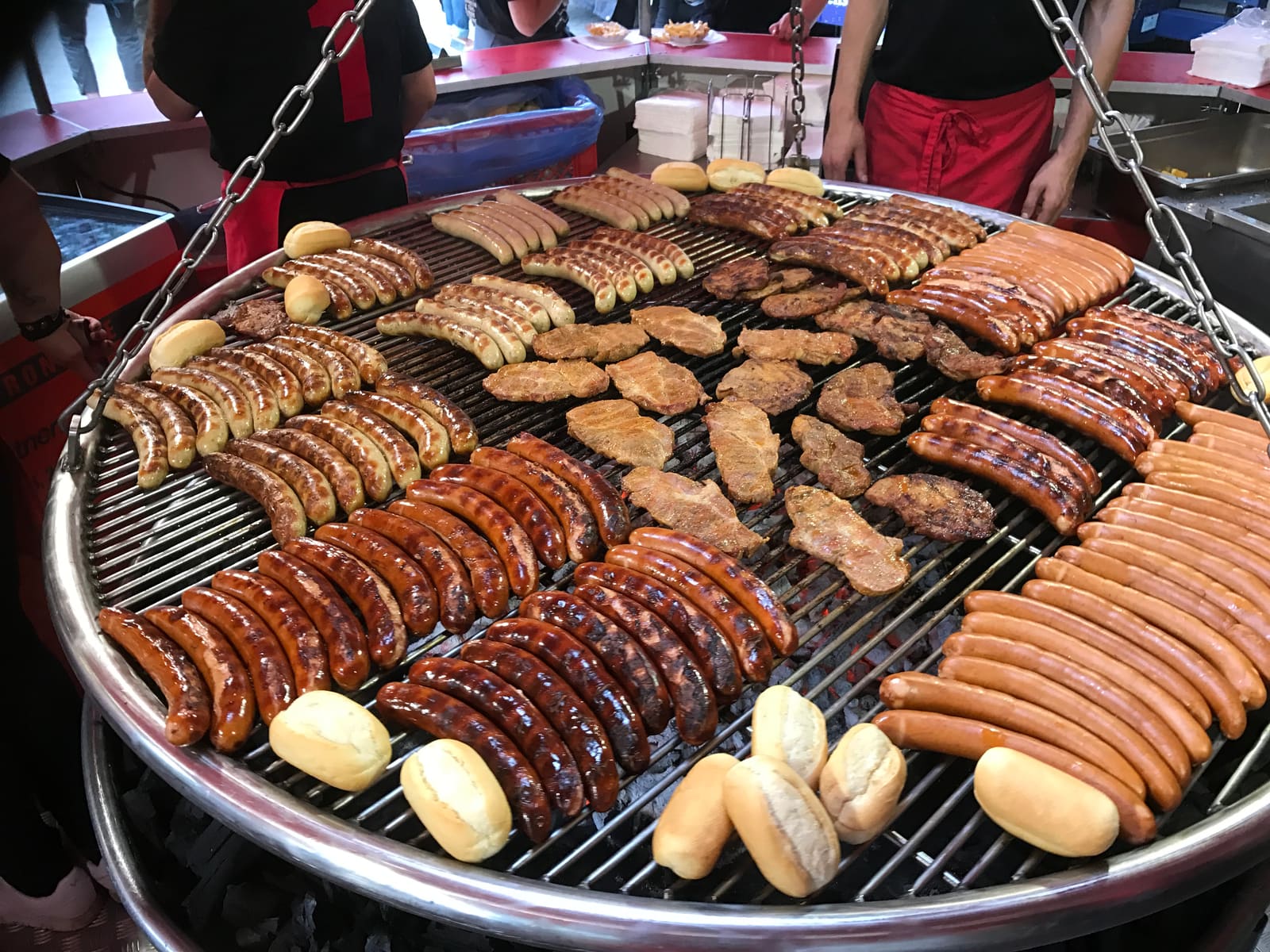 Voller Schwenkgrill mit Bratwürsten, Nackensteaks und Brötchen bei Grill-Partner Maier